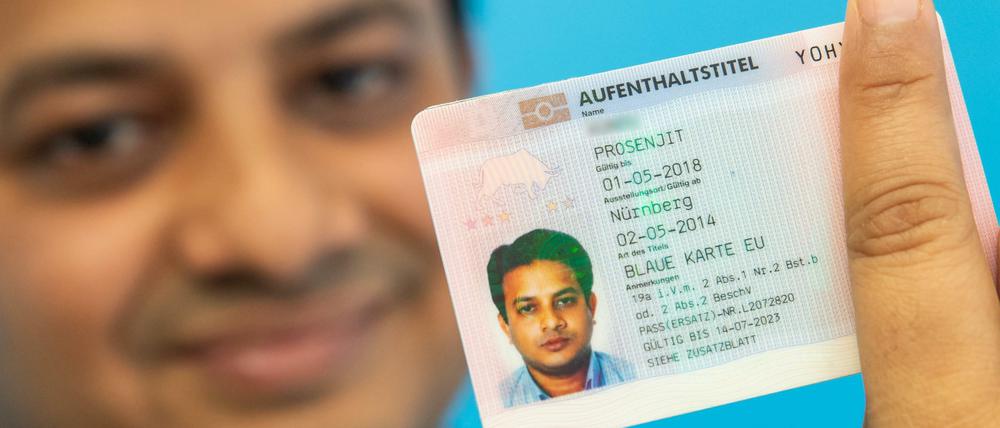 Prosenjit, Softwareentwickler aus Indien, hält seine "Blaue Karte" für ausländische Fachkräfte im Bundesamt für Migration und Flüchtlinge (Bamf) in der Hand.