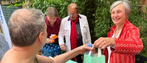 Ursula Schoen gibt bei der Aktion Warmes Essen gemeinsam mit Frank Zander Tüten mit Sonnencreme und Wasser aus.
