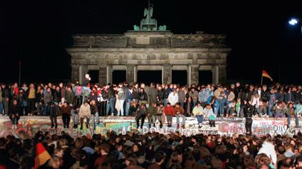 Jubelnde Menschen auf der Berliner Mauer am Brandenburger Tor am 10. November 1989.