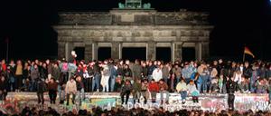 Jubelnde Menschen auf der Berliner Mauer am Brandenburger Tor am 10. November 1989.