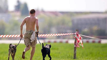 Körperkult. Ein Mann zeigt auf dem Tempelhofer Feld, was er außer zwei Hunden noch so zu bieten hat.