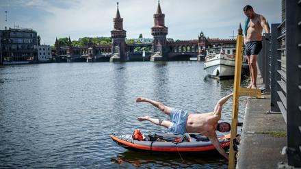 Felix (l.) und Mike genießen das hochsommerliche Wetter mit Akrobatik, Schwimmen und Paddeln an der Spree vor der Oberbaumbrücke. +++ dpa-Bildfunk +++