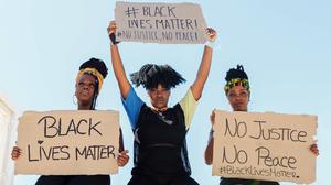 Group of multiethnic female activists protesting with raised arms in city with carton placards with black lives matter inscription and looking at camera, Model released Copyright: xPicuaxEstudiox