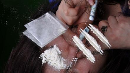 Eine Frau zieht eine Bahn Kokain durch die Nase. Häufig werden dafür Geldscheine genommen.