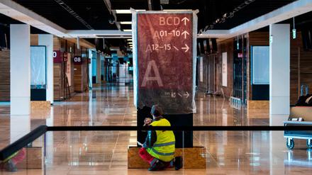 Ein Mitarbeiter reinigt eine Informationstafel am Flughafen BER, der im Oktober eröffnen soll.