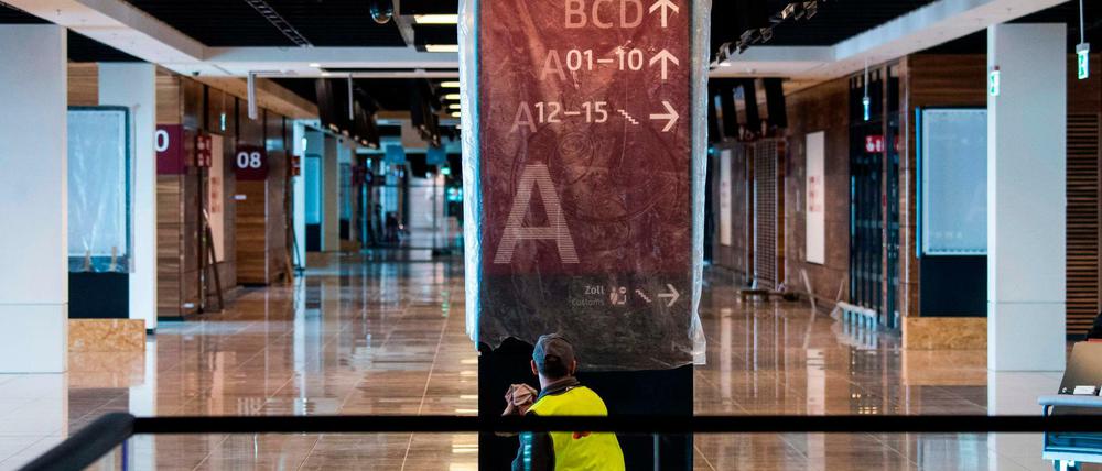 Ein Mitarbeiter reinigt eine Informationstafel am Flughafen BER, der im Oktober eröffnen soll.