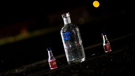  Eine leere Wodkaflasche und zwei kleine Schnapsflaschen stehen an einer Straße im Regen. 
