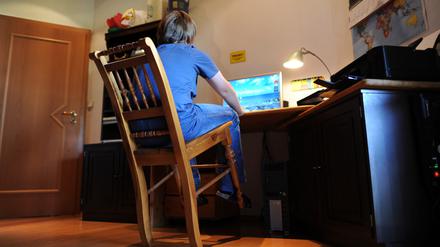 Ein Junge sitzt an einem Schreibtisch und wackelt mit dem Stuhl.