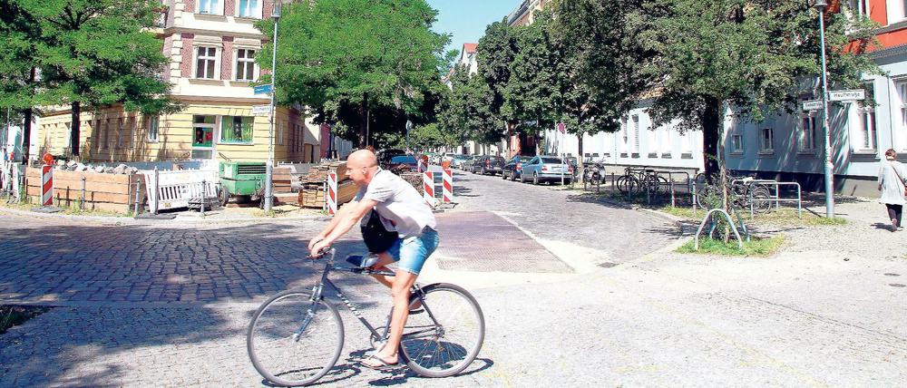 Sommerlich gekleideter Radfahrer vor Altbaukulisse im Kaskelkiez in Berlin-Lichtenberg.