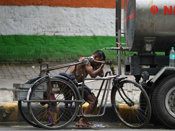 Ein Mann kühlt sich in Delhi an einem Wassertruck ab.