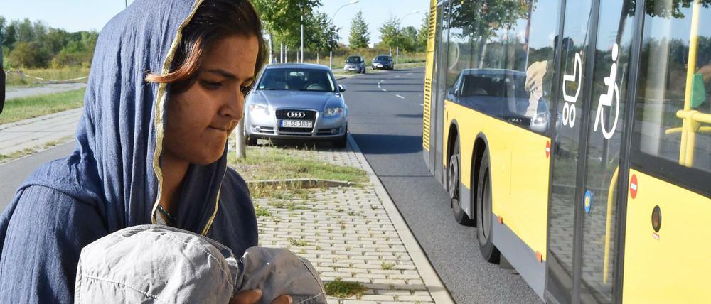 Eine Frau aus Sri Lanka geht am 08.09.2015 am Bahnhof in Schönefeld (Brandenburg) mit ihrem Kind zu einem bereit stehenden Bus. Mit einem Zug aus München kamen 450 Flüchtlinge, die in verschiedenen Notunterkünften in Berlin untergebracht werden. 