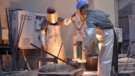 Arbeiter stehen in der Bildgießerei Noack in Berlin und holen geschmolzenes Metall aus einem Ofen. (Archivbild)