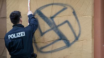 Ein Polizist sichert aan der Fassade des Wohnhauses von AfD-Vize Alexander Gauland Spuren an einem gesprühten Hakenkreuz.