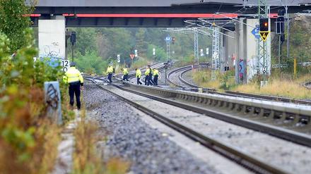 Polizeibeamte untersuchen in Berlin die Umgebung einer Bahnstrecke, an Brandsätze entdeckt wurden. Die Gleise sind nicht durch Zäune gesichert. 
