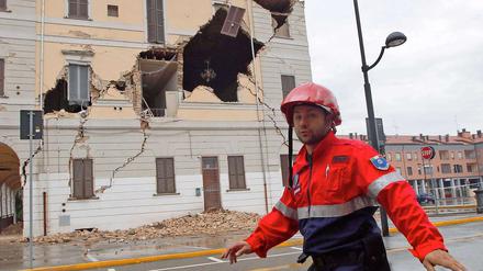 Ein Helfer des Katastrophenschutzes geht in St. Agostino an einem beschädigten Haus vorbei. 