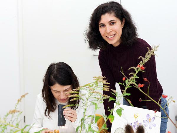 Mira O'Brian und eine Kursteilnehmerin, die Pflanzen unter einem Mikroskop anschaut.