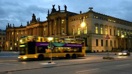 Ein Bus fährt vorbei an der Alten Bibliothek (Kommode) am Bebelplatz in der Straße Unter den Linden im Berliner Bezirk Mitte. 