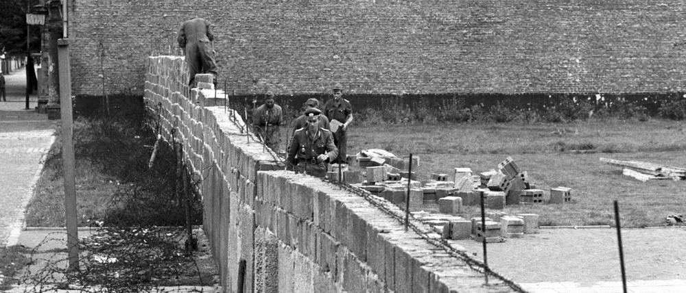 Volkspolizisten und Arbeiter der DDR beim Errichten der Berliner Mauer im Norden Berlins an der Grenze zum westberliner Bezirk Reinickendorf. 