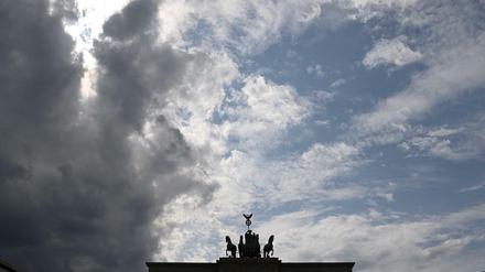 Ein graues Wolkenband zieht hinter der Silhouette der Quadriga auf dem Brandenburger Tor auf. 