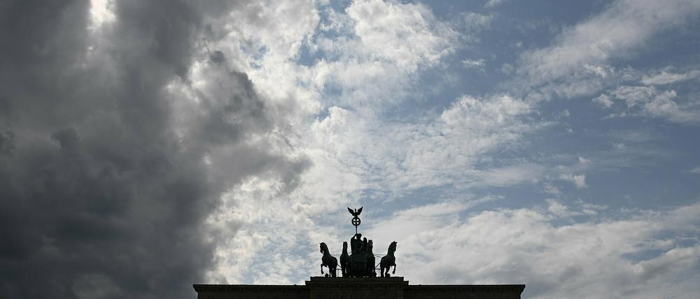 Ein graues Wolkenband zieht hinter der Silhouette der Quadriga auf dem Brandenburger Tor auf.