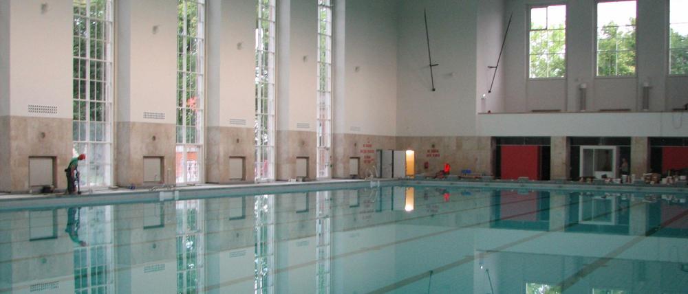 Im glasklaren Wasser des 50 Mal 25 Meter großen Beckens spiegeln sich die bodentiefen Fenster der Halle.