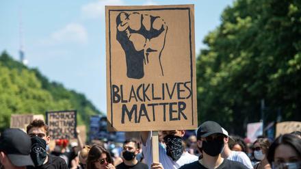 Bei der „Black Lives Matter"- Demonstration an der Siegessäule hält ein Teilnehmer ein Plakat.