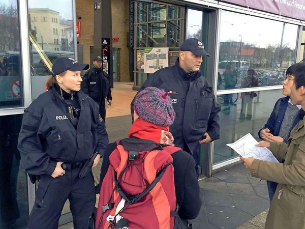 Polizisten sichern einen Eingang des Hauptbahnhofes in Potsdam, während sie Fragen der Touristen beantworten.