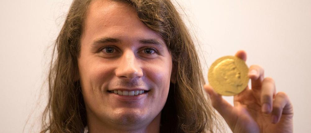 Peter Scholze, Mathematiker aus Berlin, zeigt auf dem Internationalen Mathematiker-Kongress 2018 seine Medaille. 