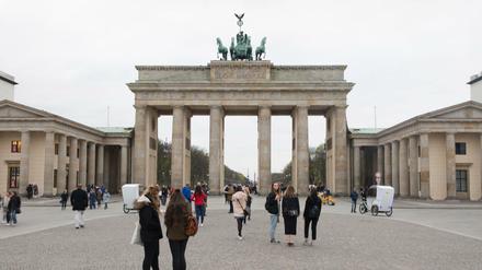 Touristen stehen vor dem Brandenburger Tor. 