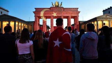 Die Menschen stehen zusammen vor dem Brandenburger Tor, an das die Flagge der Türkei gestrahlt wird.