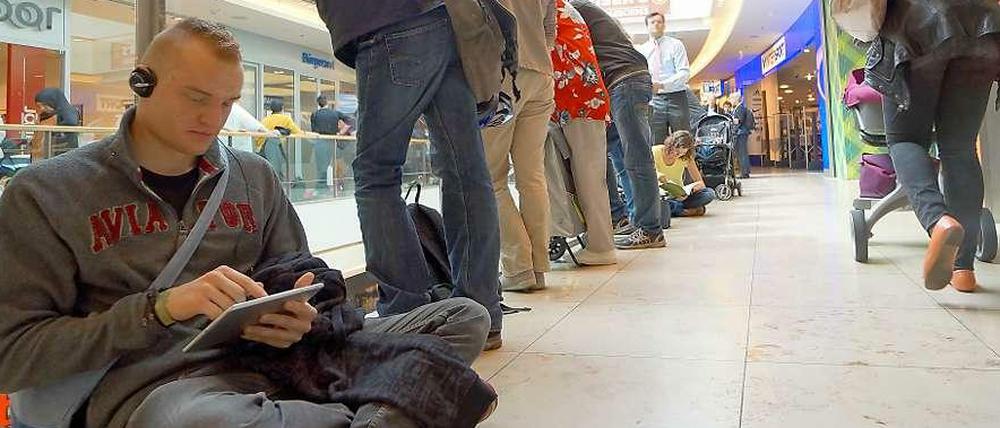 Andrang in den Arcaden. Vor der Wartenummernausgabe im neuen Bürgeramt bilden sich lange Menschenschlangen. Wer nicht stehen will, setzt sich auf den Boden.