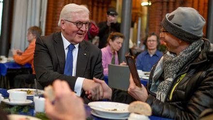 Bundespräsident Frank-Walter Steinmeier (l, SPD) unterhält sich mit Bedürftigen bei Tisch.