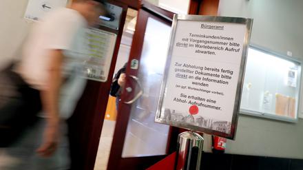 Menschen gehen im Rathaus Spandau im Bürgeramt an einem Hinweisschild für die Terminvergabe vorbei. 