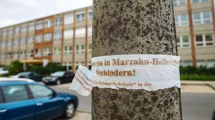 Ein zerrissenes Plakat mit der Aufschrift "Asylbewerberheim in Marzahn-Hellersdorf verhindern!" hängt an einem Laternenpfahl vor der geplanten Notunterkunft für Flüchtlinge im ehemaligen Max-Reinhardt-Gymnasium in Hellersdorf.
