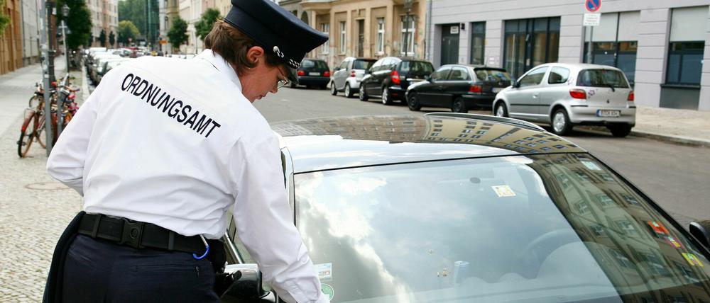Eine Mitarbeiterin der Ordnungsamtes verteilt Strafzettel an Falschparker in Berlin.