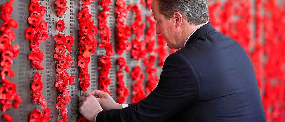 Großbritanniens Premierminister David Cameron befestigt Poppies an einer Weltkriegs-Gedenktafel.