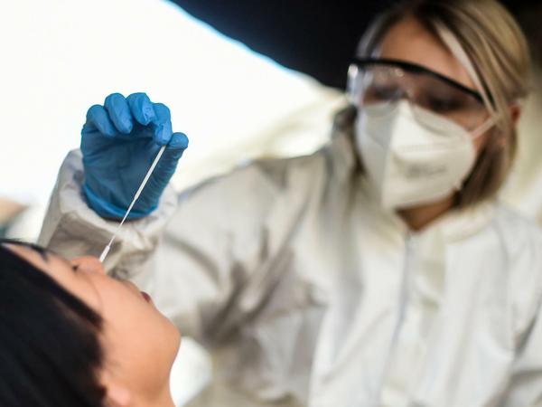 Eine Mitarbeiterin im Testzentrum Kit Kat Club nimmt einen Nasenabstrich für einen Corona-Schnelltest.