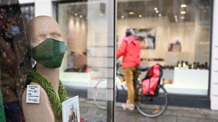 Kurz vor Weihnachten 2020: Eine Radfahrerin betrachtet die Auslage eines geschlossenen Geschäftes am Kurfürstendamm. Nur wenige Passaten waren auf der sonst so beliebten Shopping-Meile unterwegs.