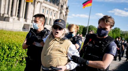 Eine Teilnehmerin wird von Polizeibeamten mit Mund-Nasen-Schutz vor dem Reichstagsgebäude am Rande einer Demonstration gegen eine Impfpflicht und gegen die freiheitseinschränkenden Maßnahmen der Bundesregierung im Rahmen der Ausbreitung des Coronavirus abgeführt.