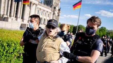 Eine Teilnehmerin von Corona-Protesten im März wird vor dem Reichstagsgebäude abgeführt.