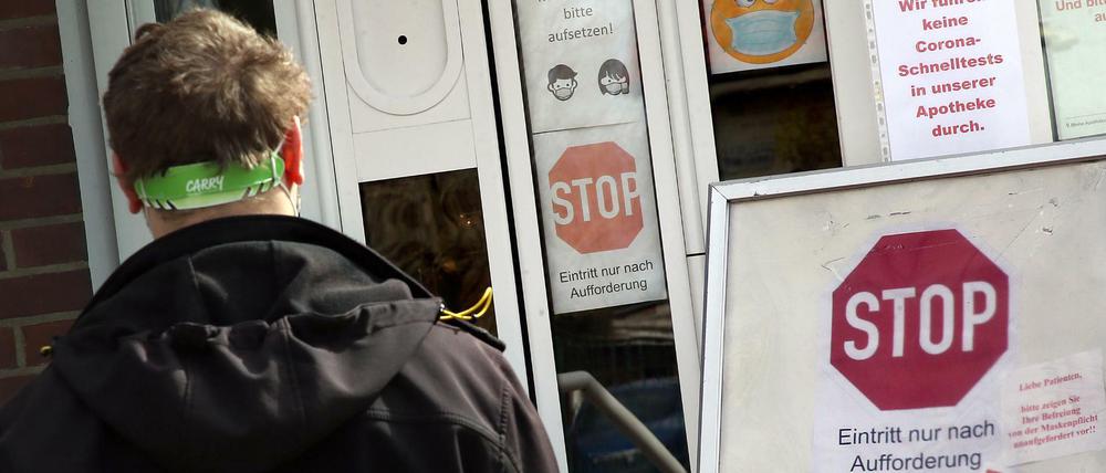 Ein Mann steht im Berliner Ortsteil Kaulsdorf im Bezirk Marzahn-Hellersdorf vor einer Apotheke, die er nur nach Aufforderung betreten darf.