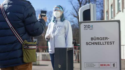 Eine Mitarbeiterin der Betreiber-Firma 21Dx GmbH und ein Bürger stehen vor einem Corona-Schnelltestzentrum in der Lehrter Straße hinter einem Schild mit der Aufschrift «Bürger-Schnelltest».