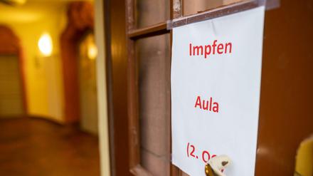 Ein Hinweisschild mit der Aufschrift: "Impfen Aula" hängt an einer Tür in einer Schule.