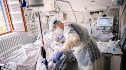 Ein Intensivpfleger versorgt auf der Intensivstation eines Krankenhauses eine an Covid-19 erkrankte Patientin.
