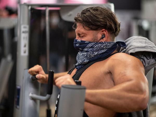 Kraftakt: Ein Mann mit Mundschutz trainiert in einem Fitnessstudio der Kette McFit an einer Brustpresse. In NRW haben nach ihrer Corona-Pause in der Nacht zu Montag die ersten Fitnessstudios wiedereröffnet.