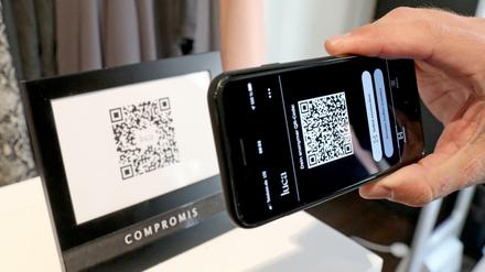 Kontaktnachverfolgung per Luca-App: Ein Mann scannt den QR-Code eines Geschäfts in Schwerin mit seinem Handy.