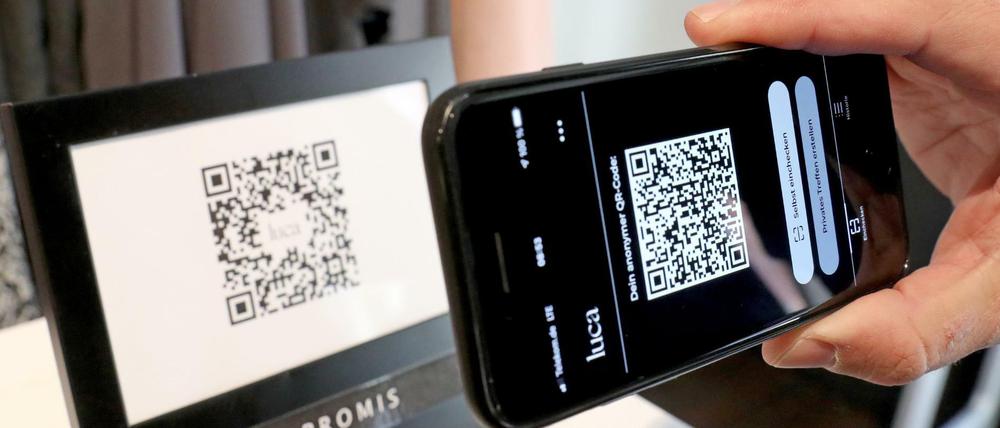 Kontaktnachverfolgung per Luca-App: Ein Mann scannt den QR-Code eines Geschäfts in Schwerin mit seinem Handy.