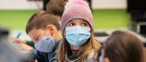 Kinder mit Mundschutzmasken sitzen im Unterricht.