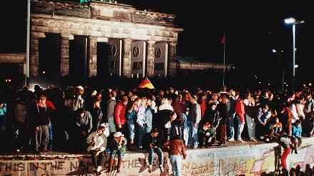 Jubelnde Menschen standen am 09. November 1989 auf der Berliner Mauer vor dem Brandenburger Tor.
