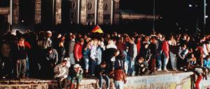 Jubelnde Menschen standen am 09. November 1989 auf der Berliner Mauer vor dem Brandenburger Tor.